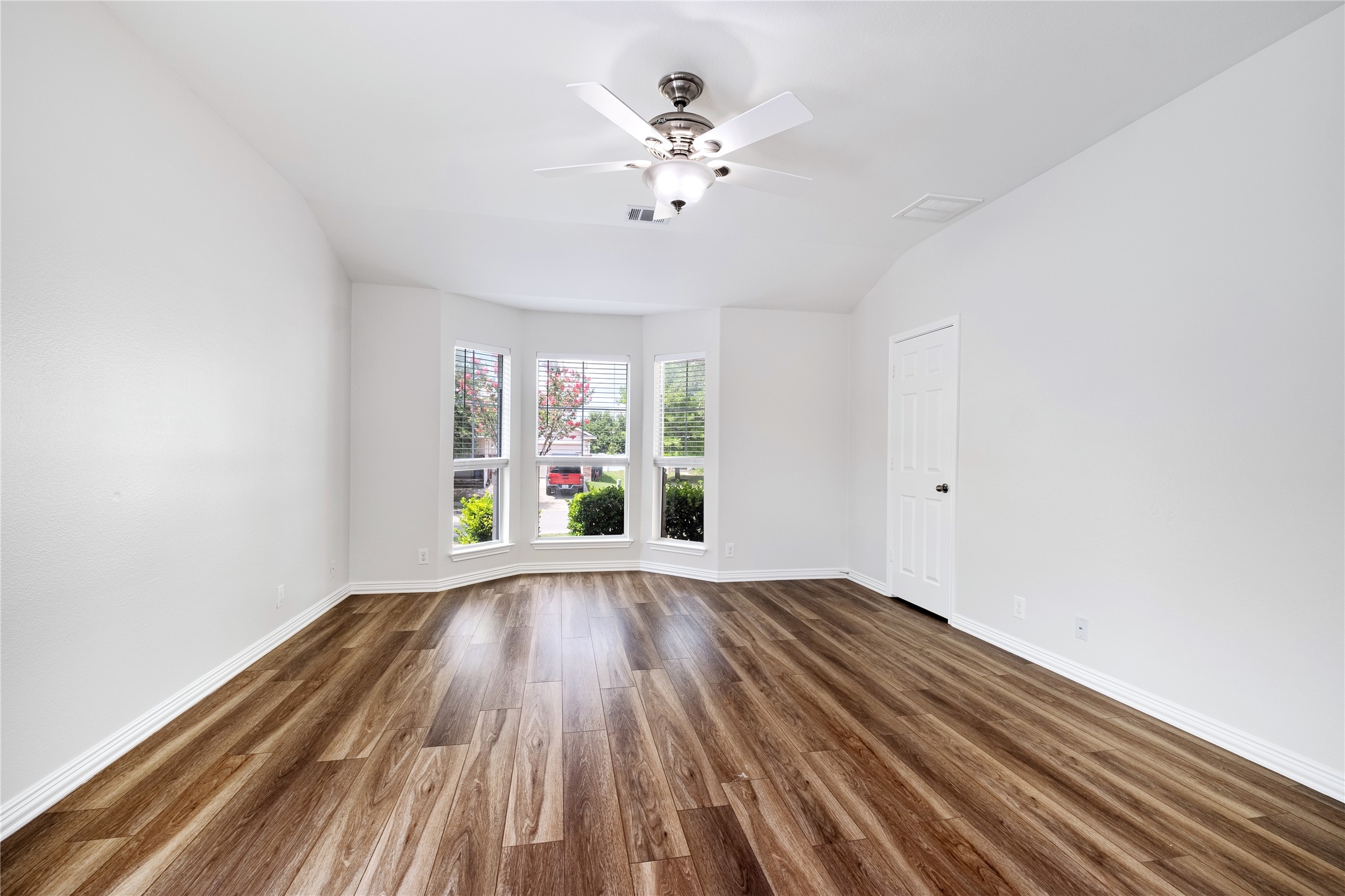 1400 Portchester Castle Path Pflugerville, TX 78660 - Photo 20 of 40 Empty room with dark wood-type flooring, vaulted ceiling, and ceiling fan