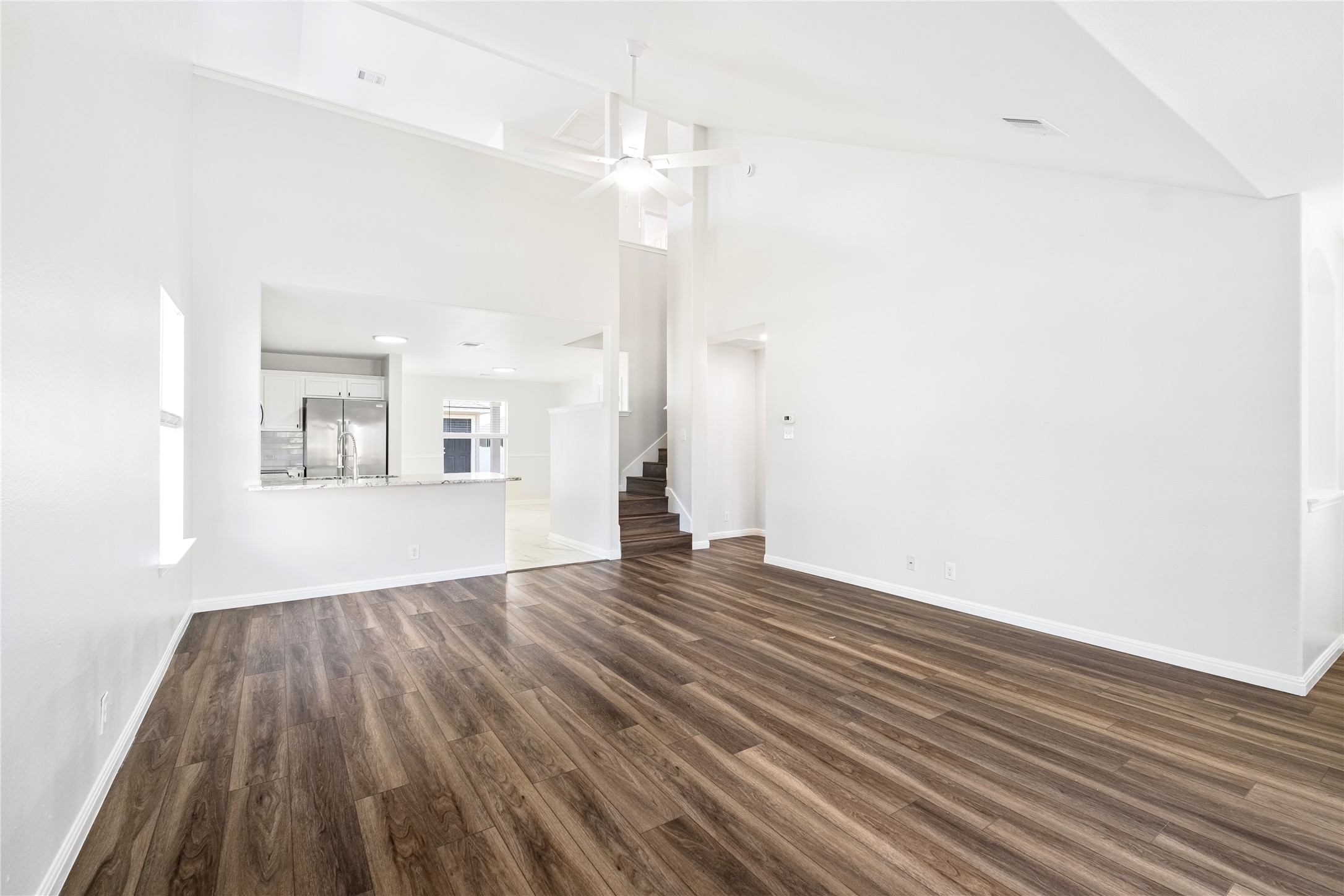 1400 Portchester Castle Path Pflugerville, TX 78660 - Photo 6 of 40 Unfurnished living room with dark wood-style flooring, lofted ceiling, and a ceiling fan