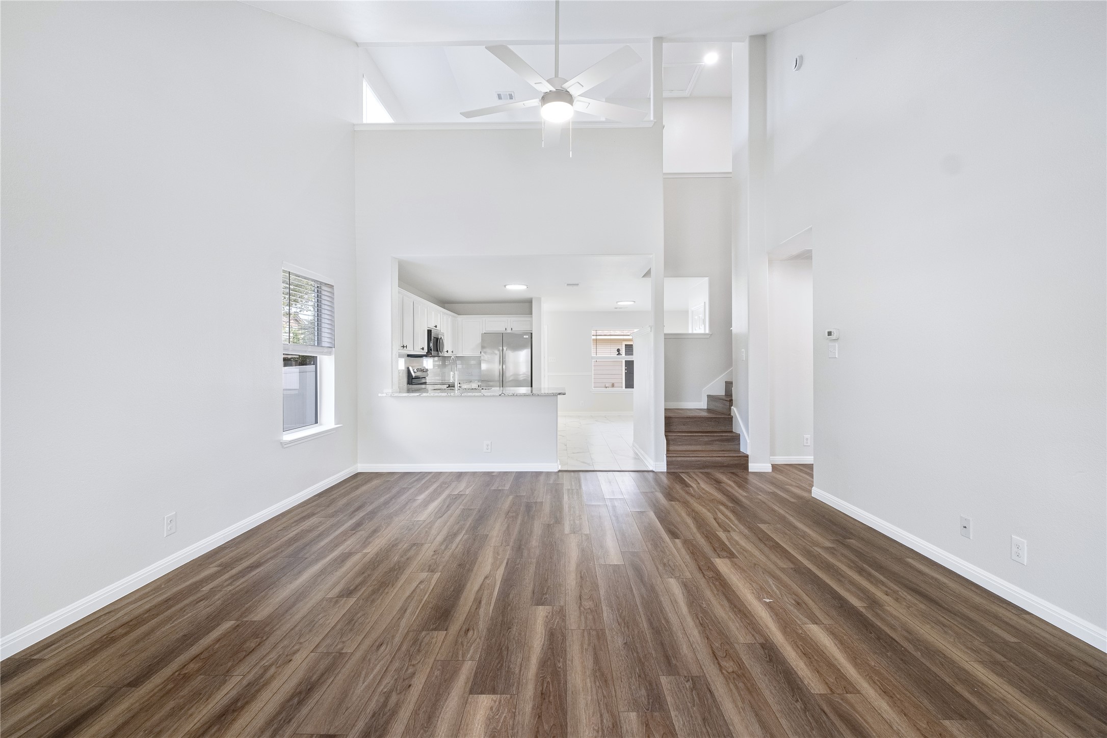 1400 Portchester Castle Path Pflugerville, TX 78660 - Photo 9 of 40 Unfurnished living room featuring dark wood-style floors, a ceiling fan, a high ceiling, and recessed lighting