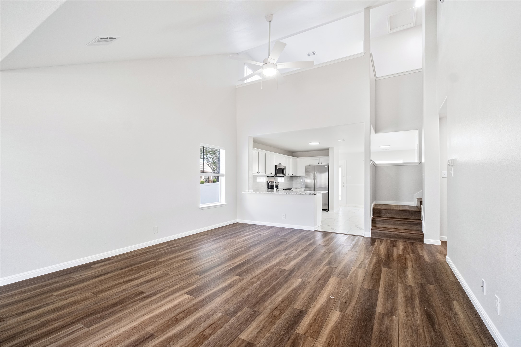 1400 Portchester Castle Path Pflugerville, TX 78660 - Photo 10 of 40 Unfurnished living room featuring dark wood-type flooring, vaulted ceiling, and ceiling fan