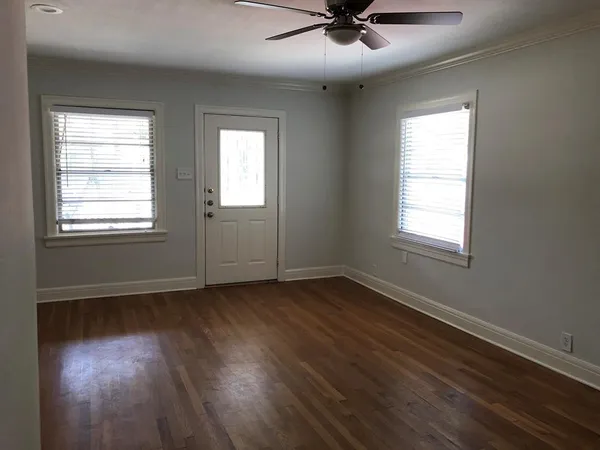 a view of an empty room with wooden floor and a window