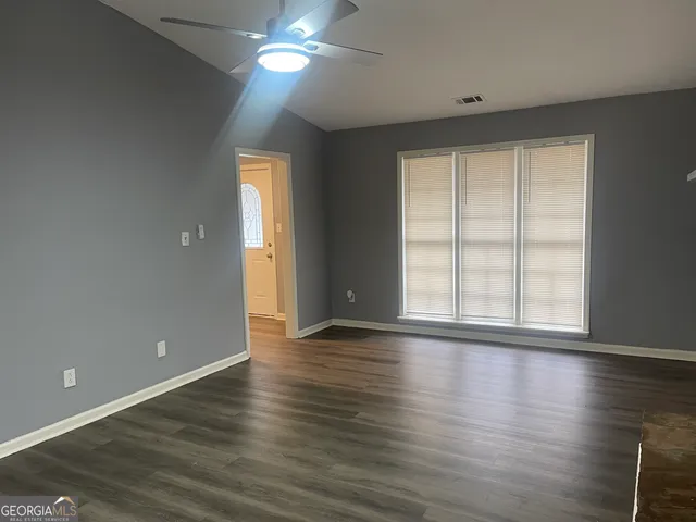 a view of an empty room with wooden floor and a window