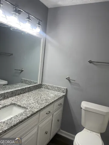 a bathroom with a granite countertop sink and a toilet
