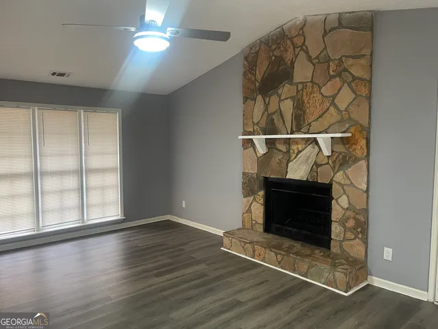 an empty room with wooden floor fireplace and windows