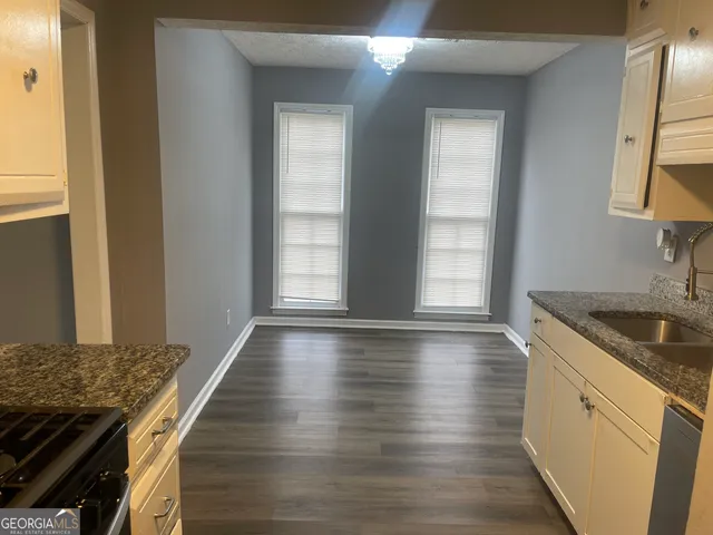a kitchen with granite countertop a sink stove and cabinets