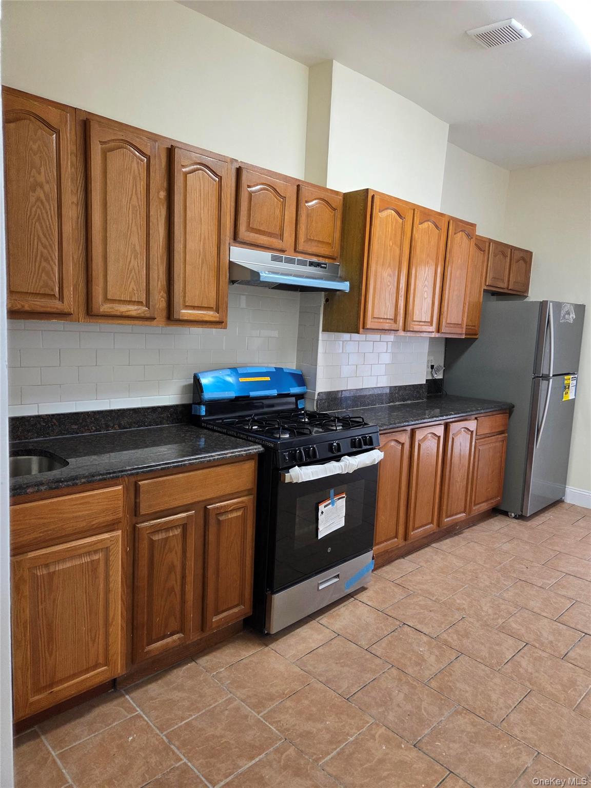 99-02 43rd Avenue Queens, NY 11368 - Photo 2 of 2 a kitchen with stainless steel appliances granite countertop a sink dishwasher stove and cabinets