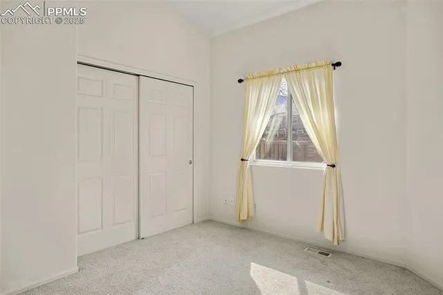 a view of an empty room with window and cabinet area