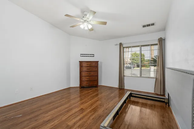 an empty room with wooden floor fan and windows