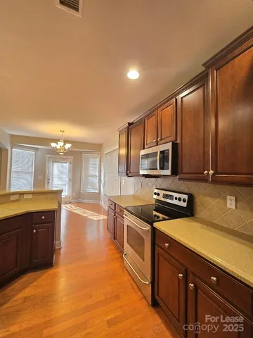 a large kitchen with stainless steel appliances wooden cabinets a stove and a sink