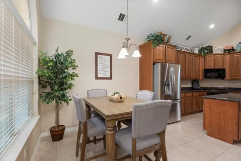 a dining room with furniture a chandelier and kitchen view