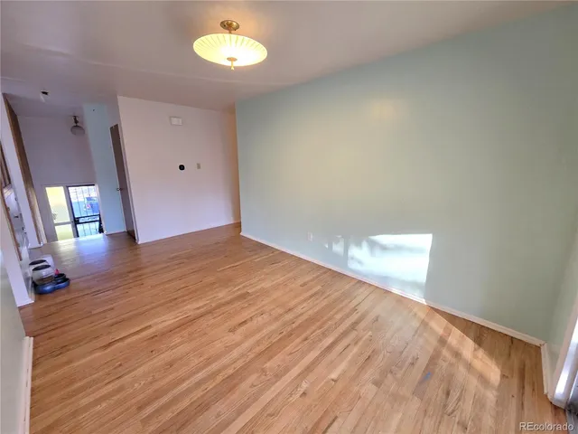 a view of empty room with wooden floor and window