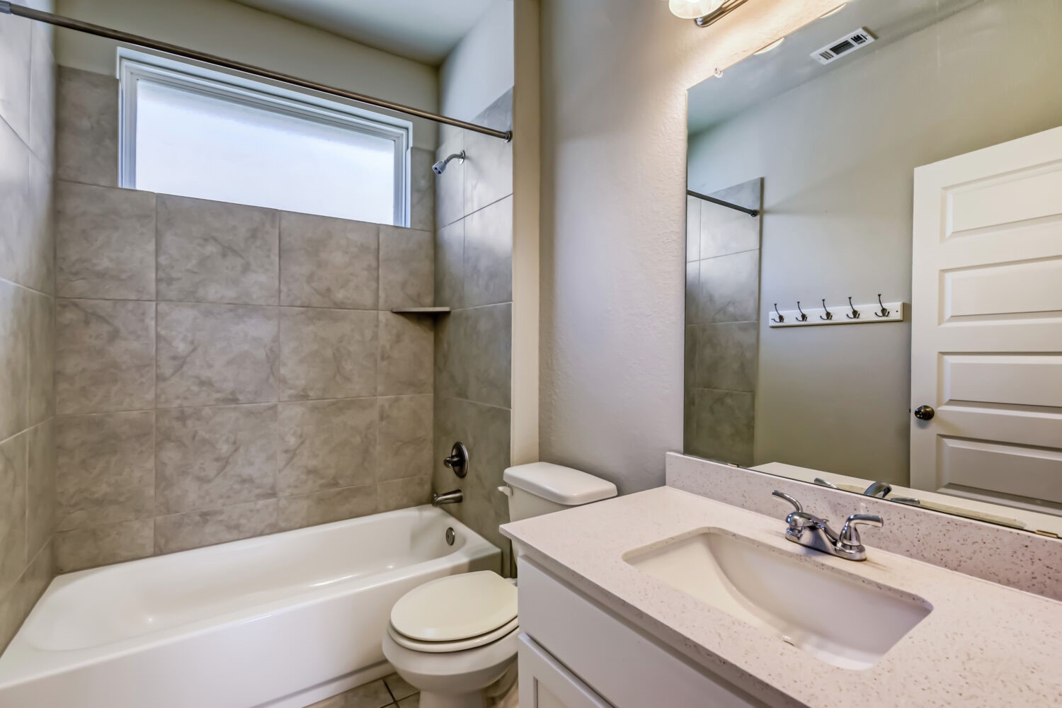 1310 Goforth Road Kyle, TX 78640 - Photo 20 of 24 Full bathroom featuring a tub/shower combination with tile surround, a built-in shelf, and a top-mounted window