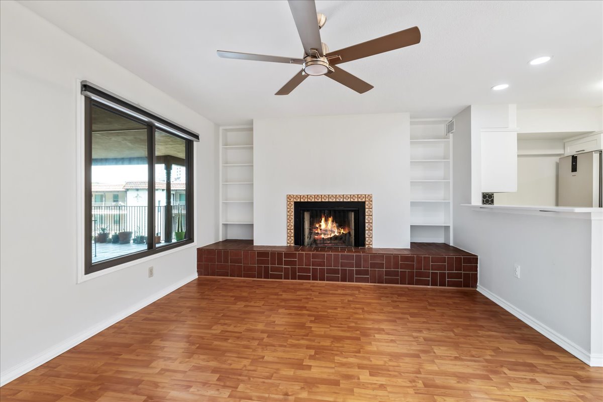505 West 7th Street, Unit 313 Austin, TX 78701 - Photo 1 of 30 Unfurnished living room featuring light wood-style flooring, baseboards, built in shelves, and a ceiling fan