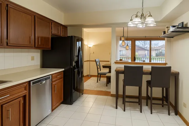 a kitchen with granite countertop a refrigerator a stove a dining table and chairs with wooden floor