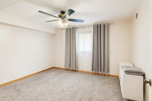 an empty room with a ceiling fan and carpet