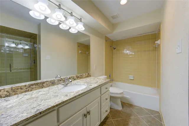 a bathroom with a granite countertop sink a toilet and a large mirror