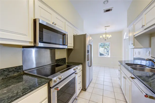 a kitchen with granite countertop a sink stainless steel appliances and cabinets