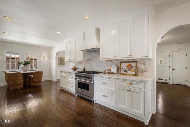 a open kitchen with stainless steel appliances granite countertop a stove top oven a sink dishwasher and a refrigerator with wooden floor