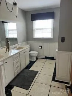 a bathroom with a double vanity sink a toilet and a window