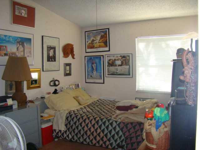 9609 Riverside Drive, Unit 9 Coral Springs, FL 33071 - Photo 6 of 15 a bedroom with a bed and a lamp on dresser with wooden floor