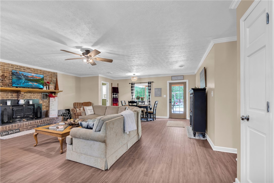 3030 Smith McGee Road Iva, SC 29655 - Photo 8 of 46 A welcoming living space features a cozy brick fireplace and rich hardwood flooring, perfect for gatherings.