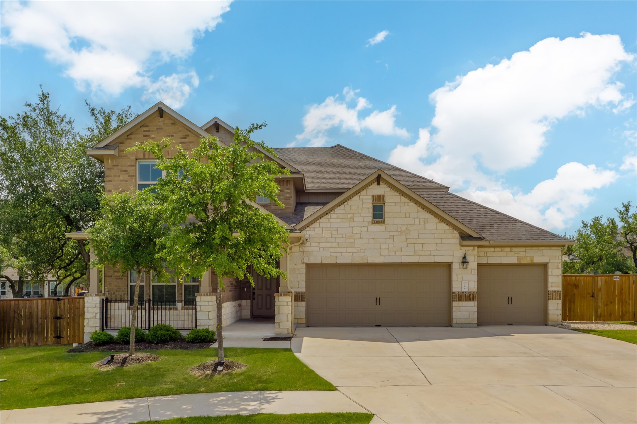 Two-story residence featuring a brick and stone facade, a two-car garage, a single-car garage, and a concrete driveway