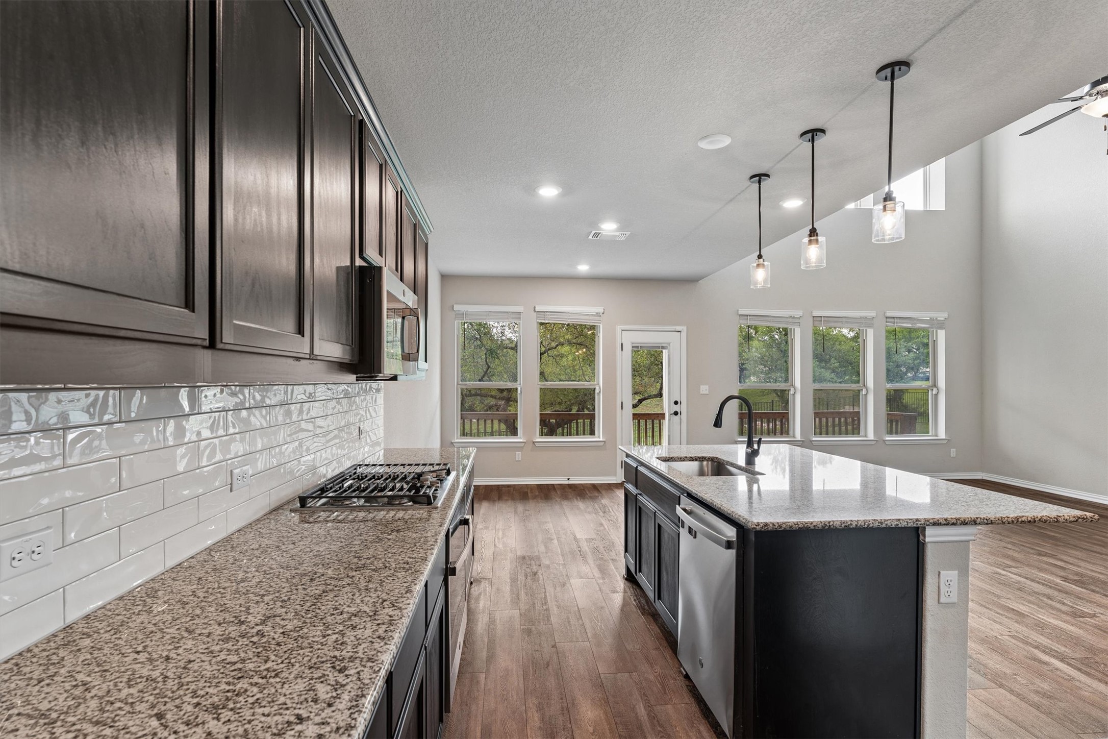 324 Autumn Oak Way Georgetown, TX 78628 - Photo 11 of 40 Kitchen featuring dark wood-finish cabinetry, light speckled countertops, and a subway tile backsplash