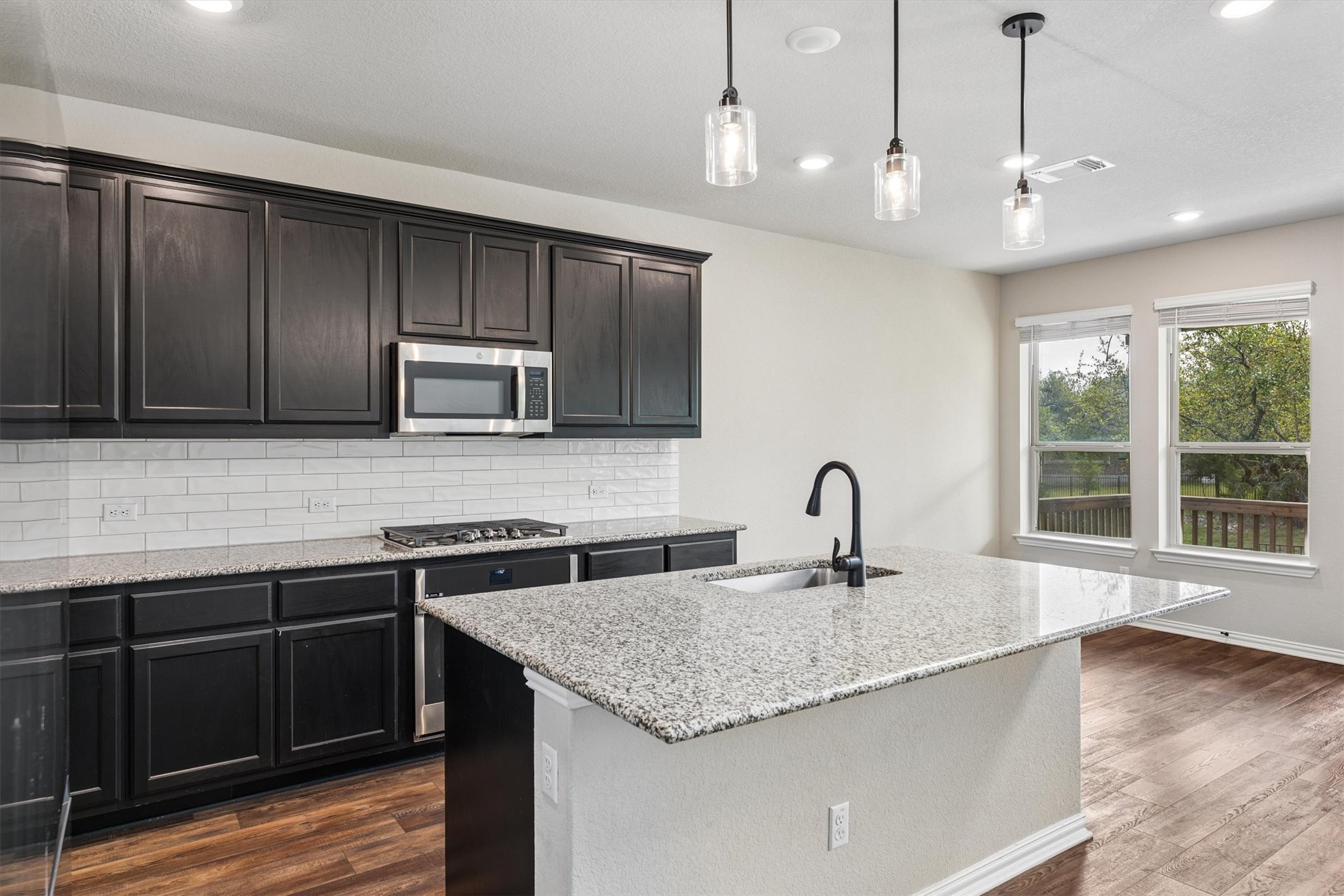324 Autumn Oak Way Georgetown, TX 78628 - Photo 12 of 40 Kitchen featuring dark wood cabinetry, a subway tile backsplash, and a gas cooktop
