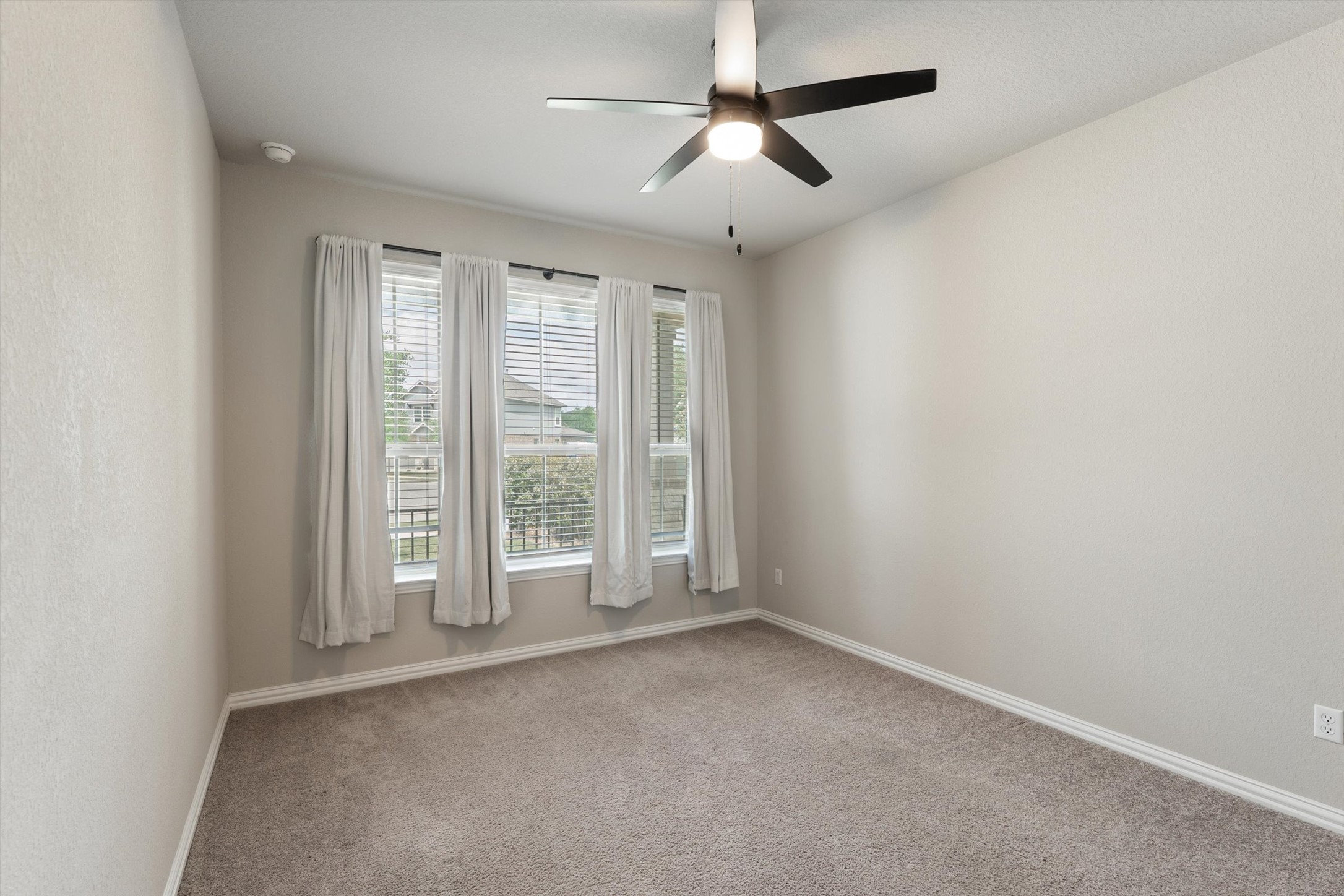 324 Autumn Oak Way Georgetown, TX 78628 - Photo 13 of 40 Neutral-toned room featuring a multi-pane window with blinds and curtains, a ceiling fan with integrated lighting, and light-colored carpeting