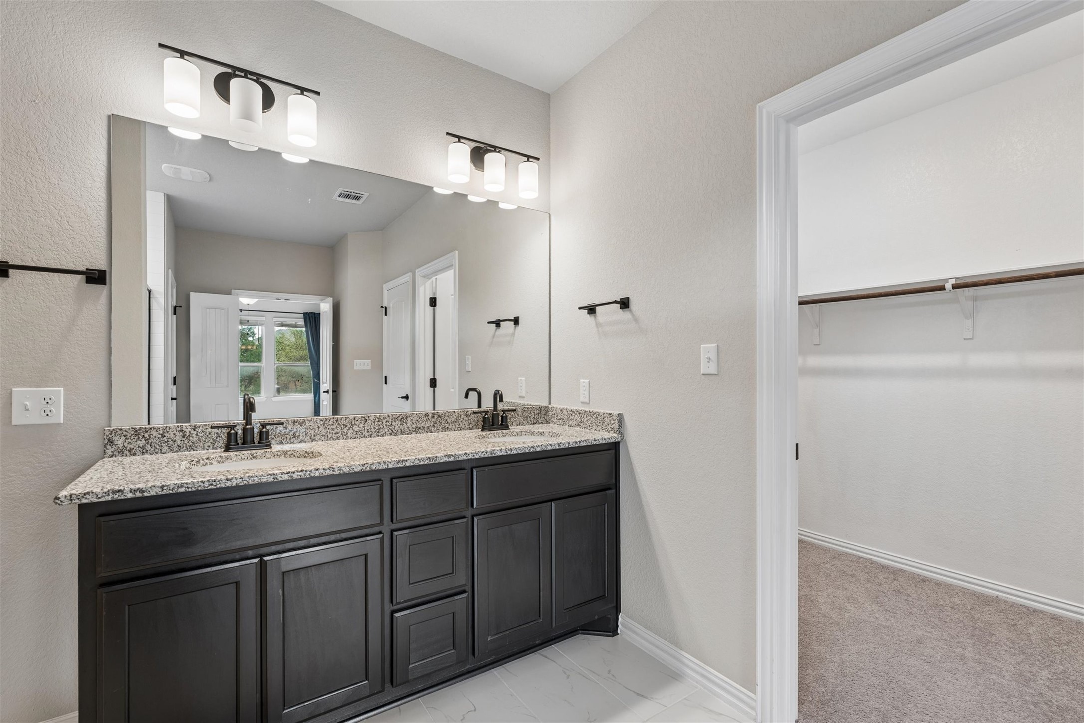 324 Autumn Oak Way Georgetown, TX 78628 - Photo 21 of 40 Double vanity with dark wood-finish cabinetry, speckled countertop, and black fixtures
