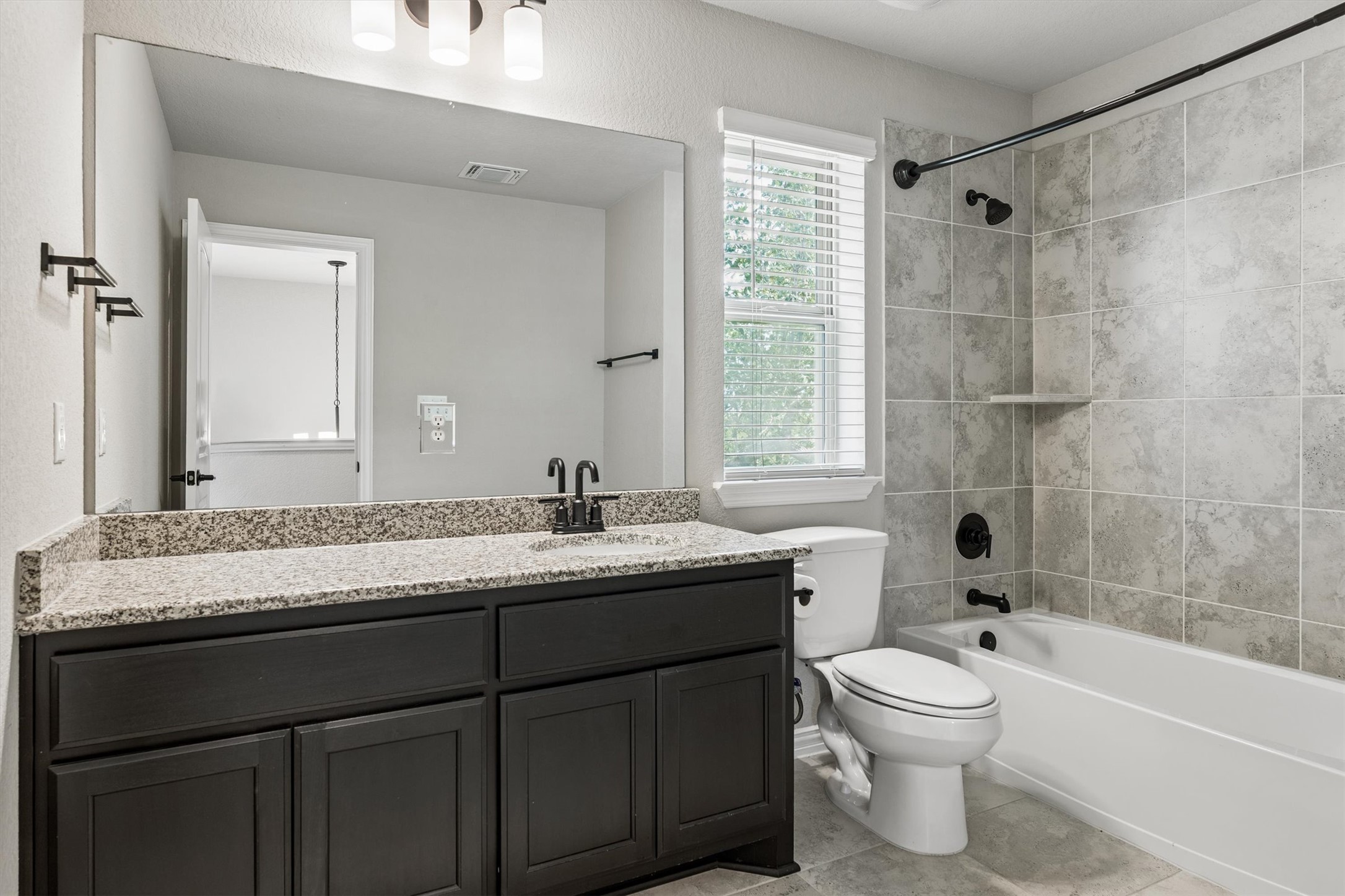 324 Autumn Oak Way Georgetown, TX 78628 - Photo 30 of 40 Full bathroom featuring a dark wood-finish vanity with a light-toned countertop, a large mirror, a tiled shower-tub combination, and a window with blinds