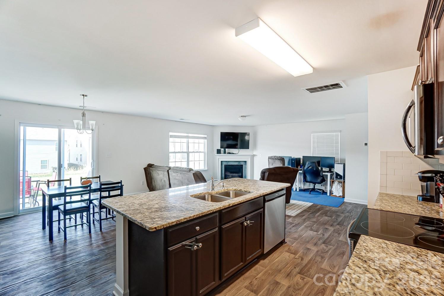 618 Bloomover Street Concord, NC 28025 - Photo 12 of 45 a open kitchen with stainless steel appliances granite countertop a stove a refrigerator a dining table and chairs with wooden floor