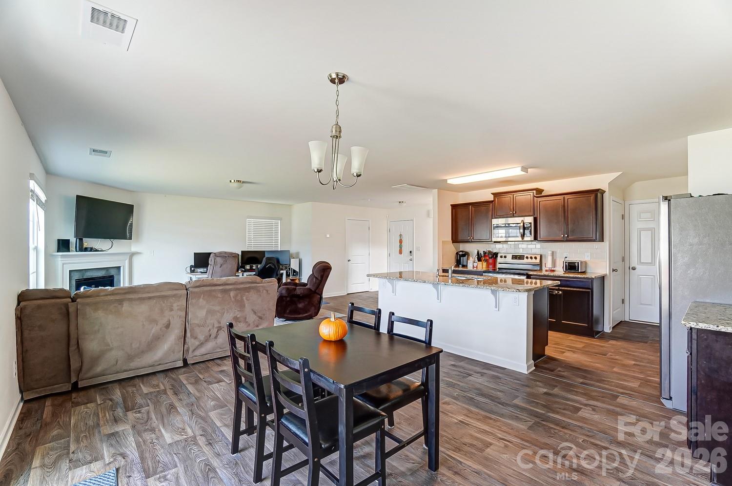 618 Bloomover Street Concord, NC 28025 - Photo 18 of 45 a kitchen with stainless steel appliances kitchen island granite countertop a refrigerator a stove a sink dishwasher a dining table and chairs with wooden floor