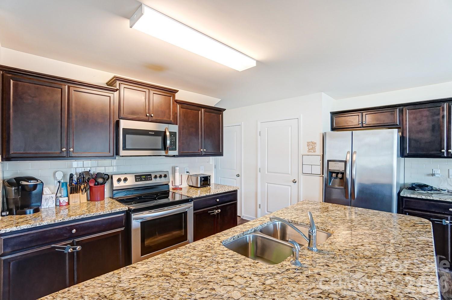 618 Bloomover Street Concord, NC 28025 - Photo 10 of 45 a kitchen with stainless steel appliances granite countertop a sink stove and refrigerator