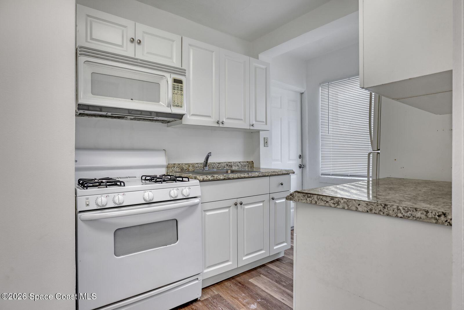 658 Young Street Melbourne, FL 32935 - Photo 14 of 77 a kitchen with granite countertop white cabinets and white appliances