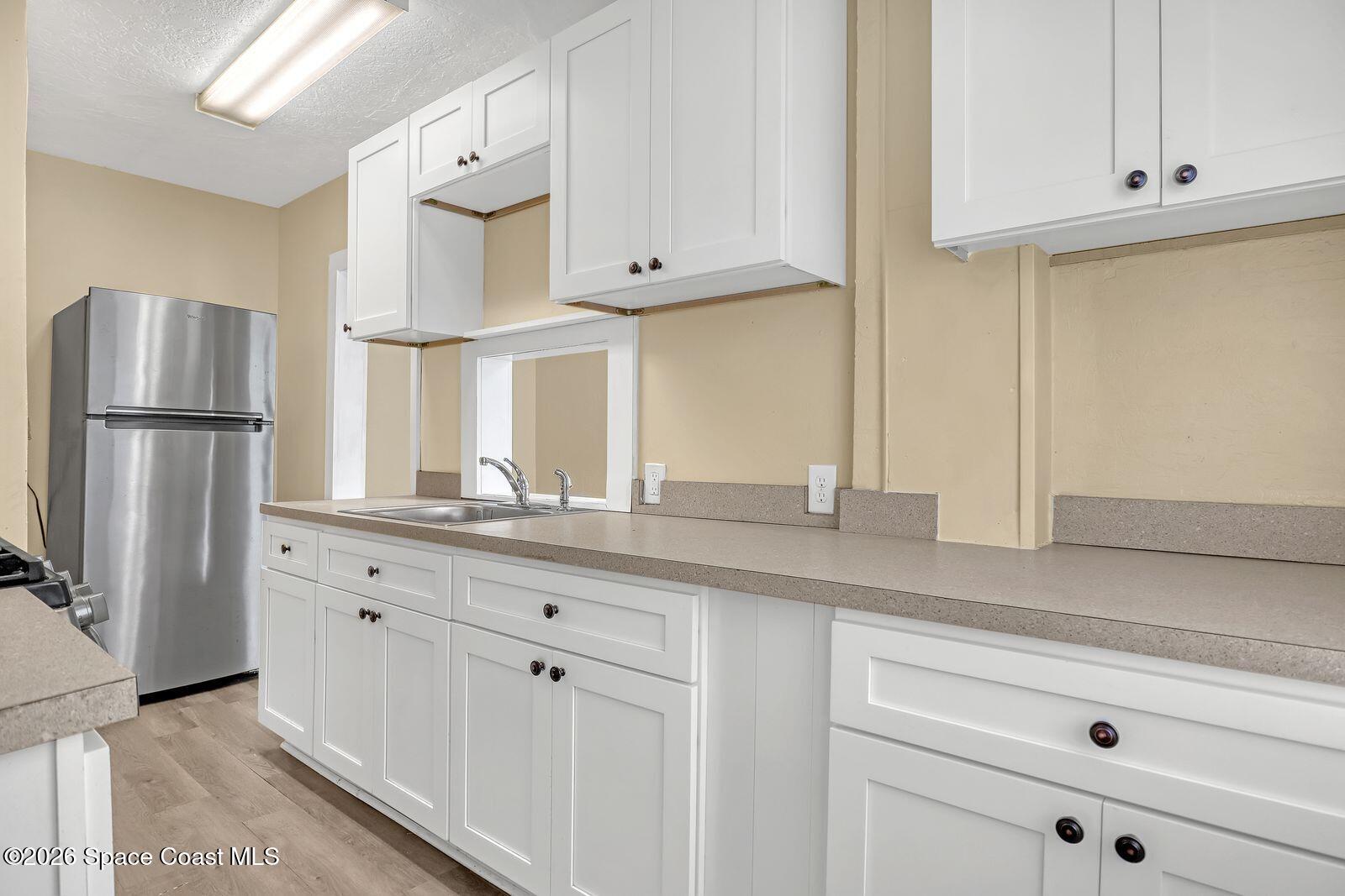 658 Young Street Melbourne, FL 32935 - Photo 31 of 77 a kitchen with granite countertop white cabinets white stainless steel appliances and sink