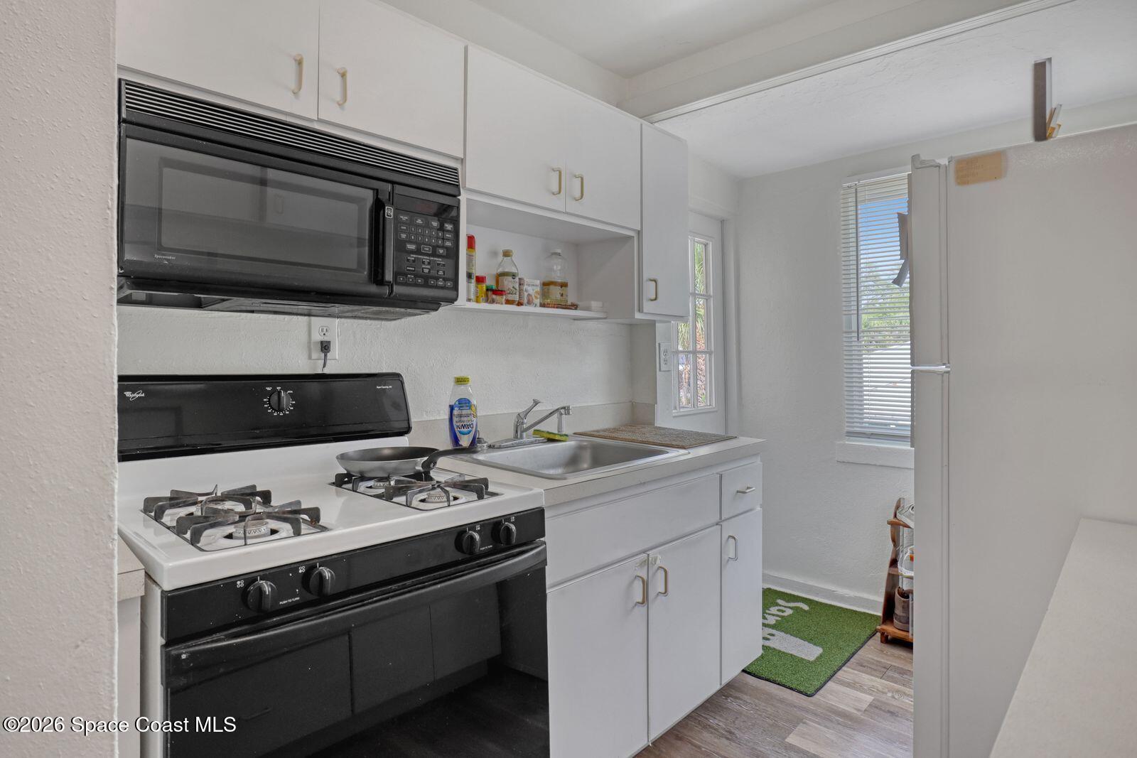 658 Young Street Melbourne, FL 32935 - Photo 45 of 77 a kitchen with stainless steel appliances a stove a microwave and cabinets