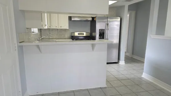 a kitchen with stainless steel appliances a refrigerator and white cabinets