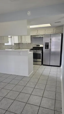 a kitchen with granite countertop a refrigerator and a stove top oven