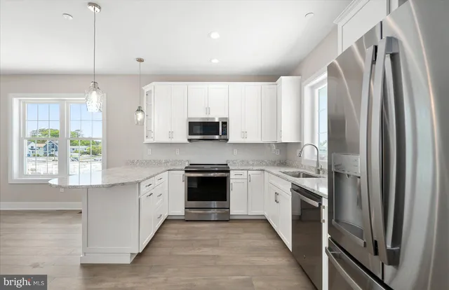 a kitchen with stainless steel appliances granite countertop white cabinets a sink and a stove