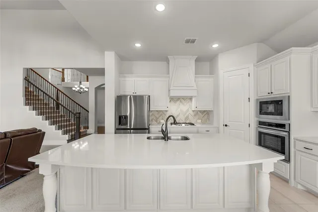 a kitchen with a sink a stove a refrigerator and white cabinets