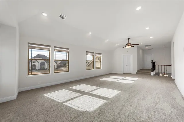 en empty room with windows and ceiling fan