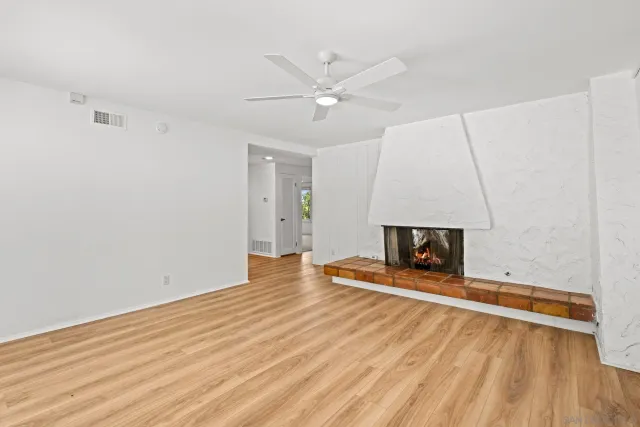 a view of an empty room with wooden floor and a fireplace