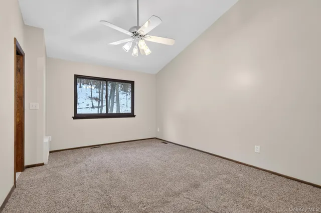 an empty room with fan and hallway