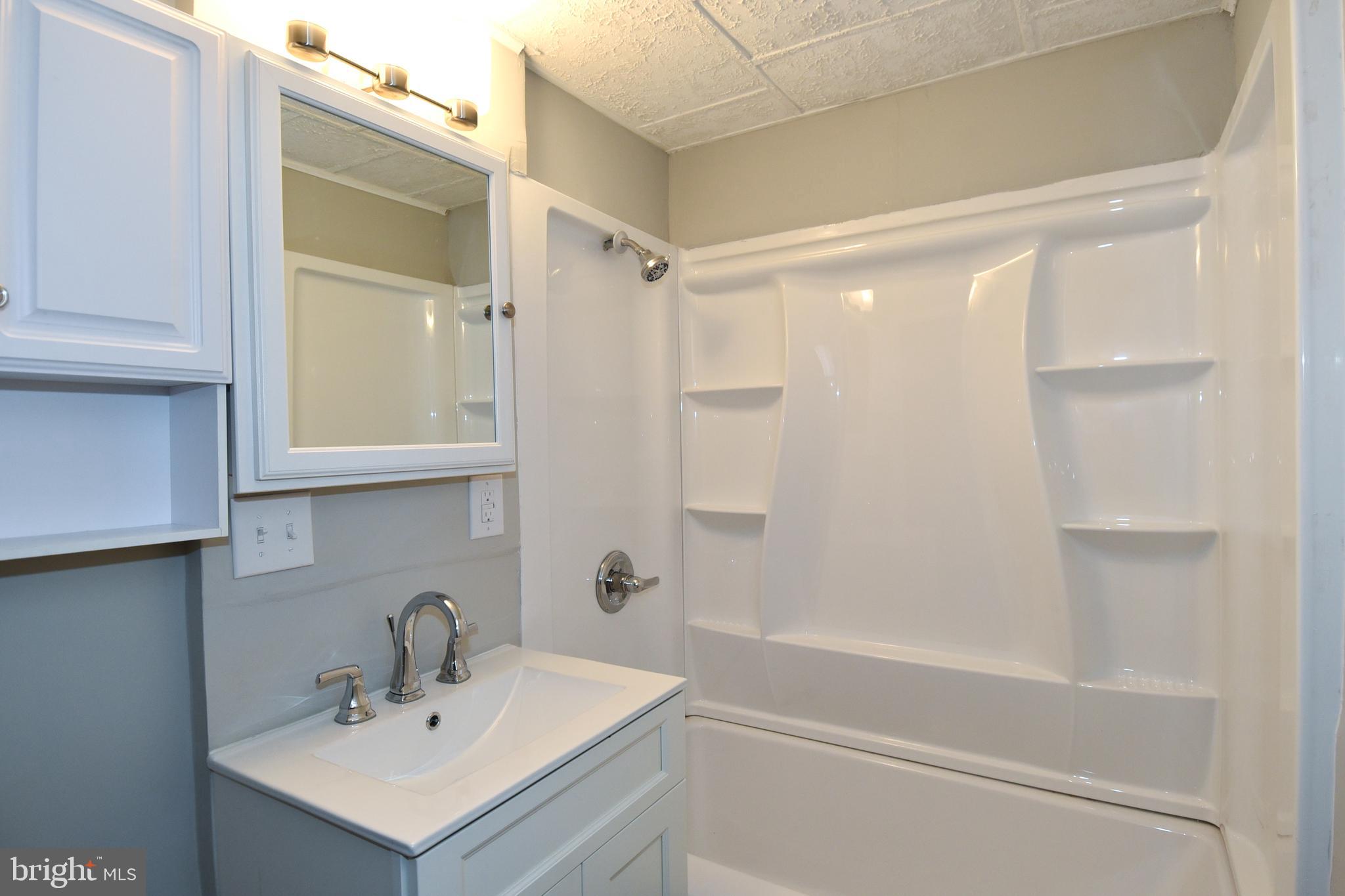 8208 Bellefonte Lane, Unit 2 Clinton, MD 20735 - Photo 36 of 38 a bathroom with a sink mirror and a shower