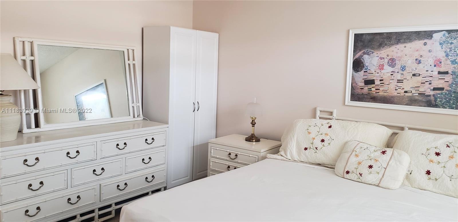 370 Racquet Club Road, Unit 103 Weston, FL 33326 - Photo 11 of 16 a bedroom with a bed and a mirror on the dresser