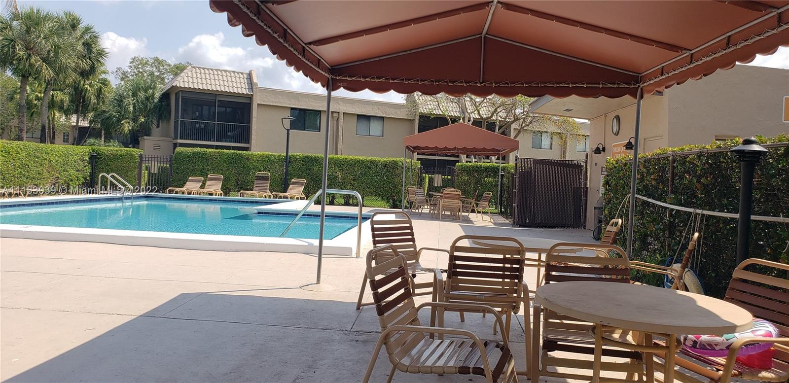 370 Racquet Club Road, Unit 103 Weston, FL 33326 - Photo 16 of 16 a view of a patio with couches table and chairs under an umbrella with a small yard