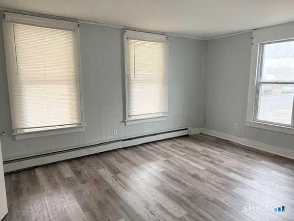 a view of an empty room with wooden floor and a window