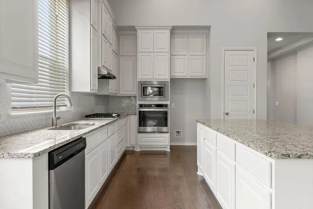 a kitchen with granite countertop a sink stove and cabinets