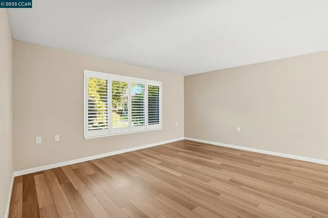a view of an empty room with wooden floor and a window